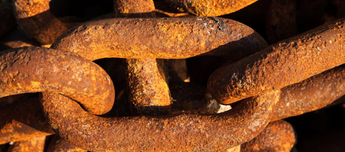 Big iron chains from an old ships anchor rusting by the harbor side close up